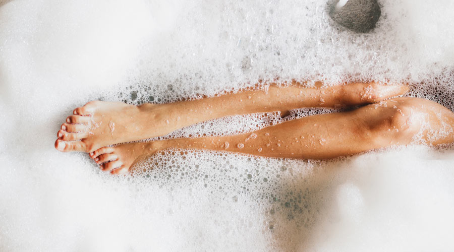 SPA: Plano fechado mostrando pernas femininas semi mergulhadas em água, dentro de uma banheira.